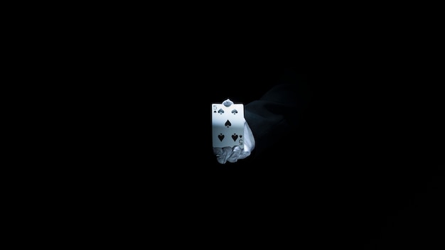 Magician's hand showing club playing card against black background