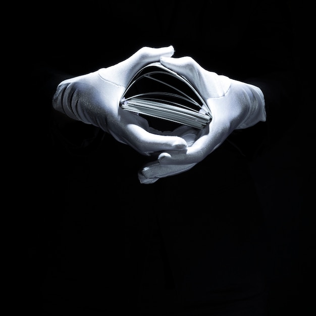 Magician's hand wearing white glove holding playing cards stack