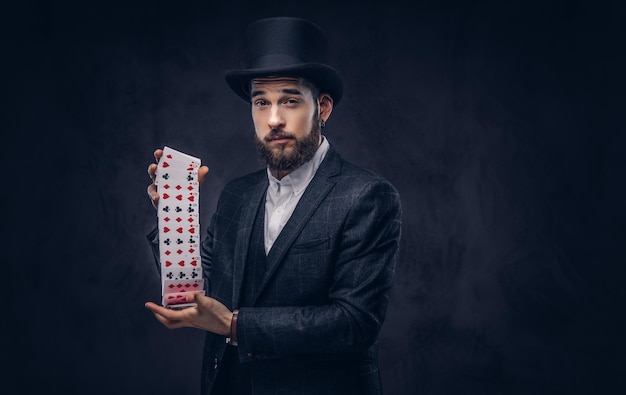 Magician showing trick with playing cards on a dark background.