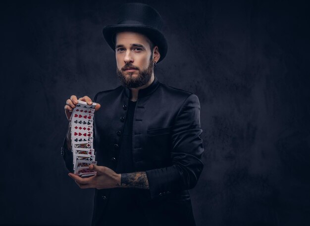 magician showing trick with playing cards on a dark background.