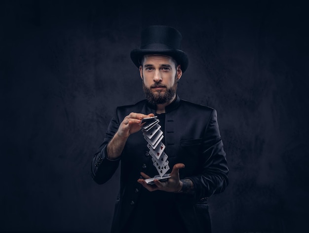 Magician showing trick with playing cards on a dark background.