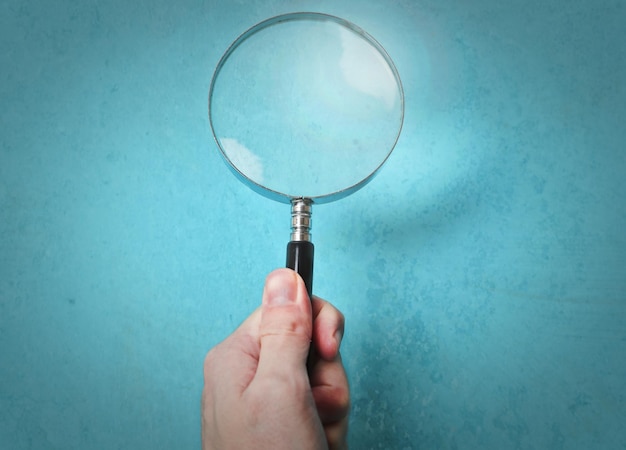 magnifying glass held on a blue background