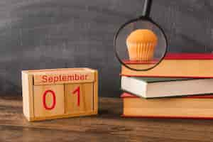 Free photo magnifying glass near calendar and books with snack