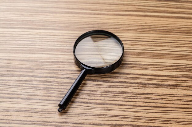 Magnifying glass on the wooden background