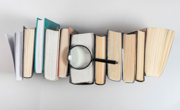 Magnifying lens over books row concept of knowledge and studying