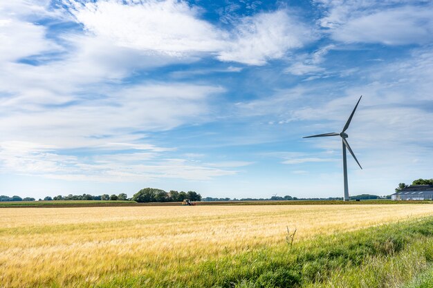 Величественный пейзажный вид на землю с ветряной мельницей для выработки электроэнергии под пасмурным небом