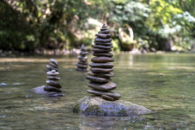 川の水の上でバランスの取れた多くの石のピラミッドの雄大なショット