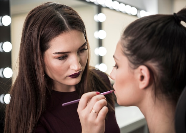 Free photo make up artist applying lipstick