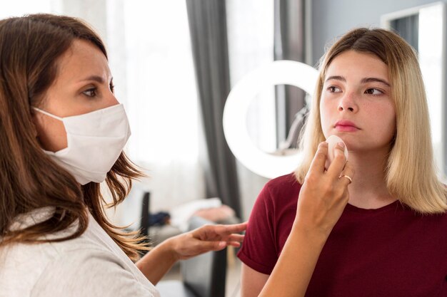 Make-up artist wearing mask and putting lipstick on client