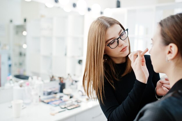 Make up artist work in her beauty visage studio salon Woman applying by professional make up master Beauty club concept