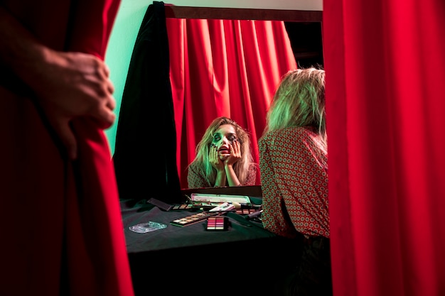 Make-up halloween joker looking in the mirror