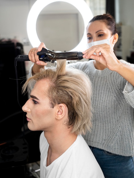 Make-up man using flat iron on his hair