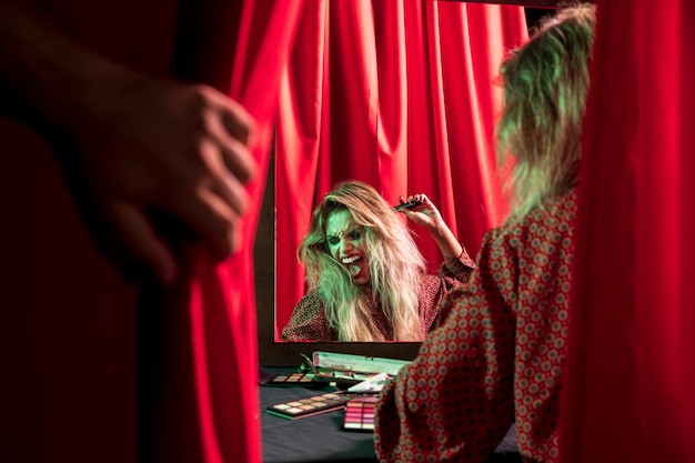 鏡の前で遊ぶハロウィーンのメイクアップ女性