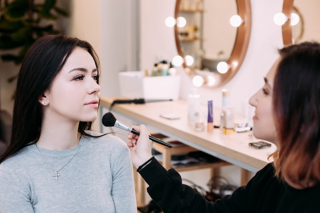 Makeup artist admires her model sitting before the mirror