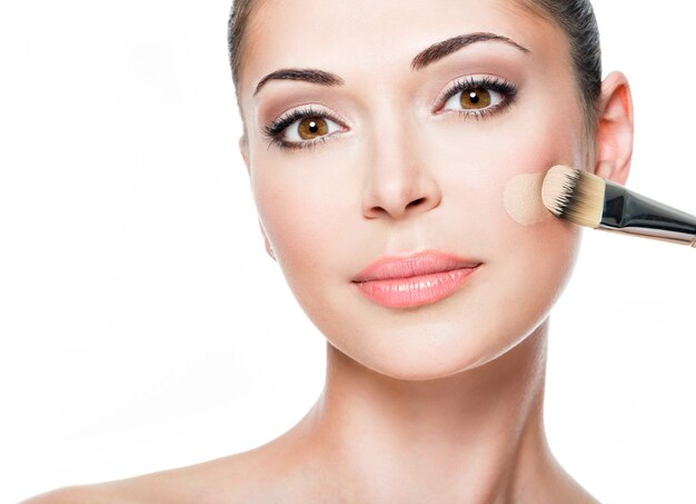 Makeup artist applying liquid tonal foundation on the face of the woman