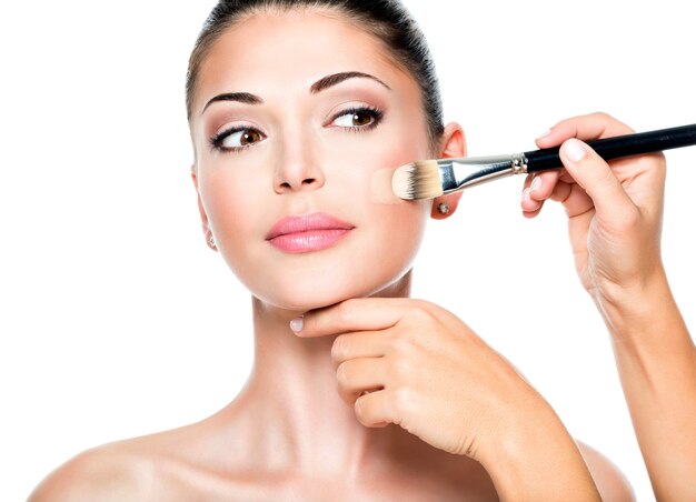 Makeup artist applying liquid tonal foundation on the face of the woman