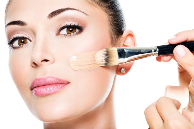 Free photo makeup artist applying liquid tonal foundation on the face of the woman