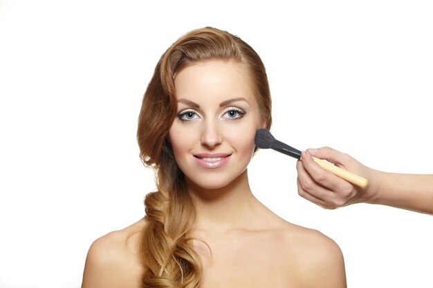 Makeup artist applying makeup to attractive blond woman