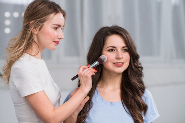 Makeup artist covering model face by powder