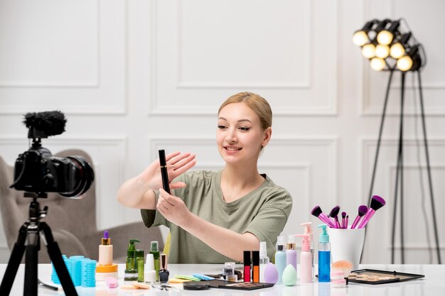 Makeup blogger pretty cute young girl recording makeup tutorial on camera with mascara