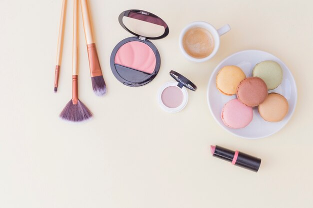Makeup brush; blusher and lipstick with breakfast on colored background