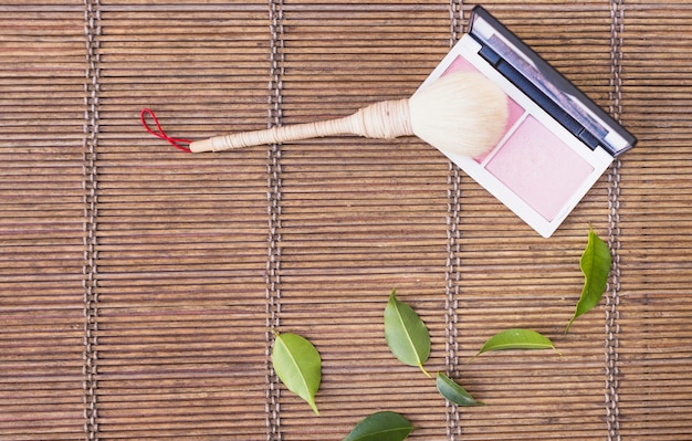 Makeup brush with palette blusher on wooden background