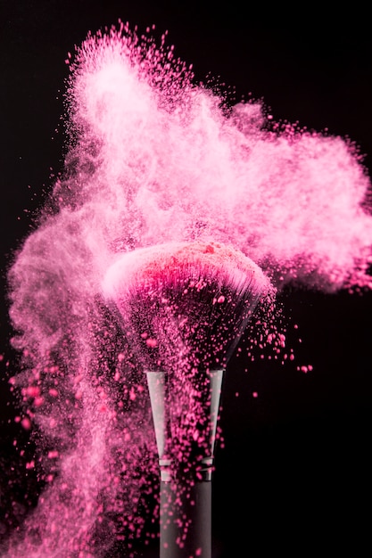 ピンクの粉を散布した化粧ブラシ