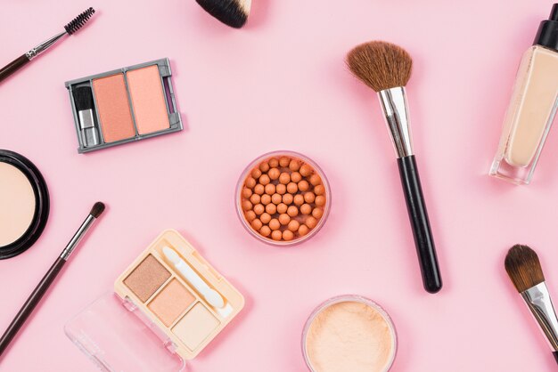 Makeup and cosmetic accessories arrangement on pink background