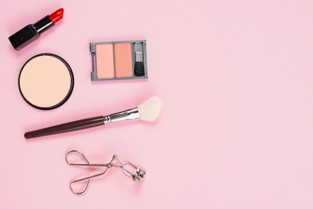 Makeup and cosmetic accessories layout on pink background