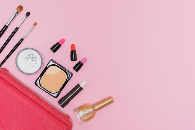 Косметика для макияжа и кисти на розовом фоне
