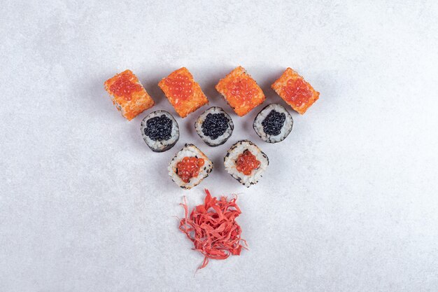 Maki, Alaska and California sushi rolls on white background with pickled ginger. 