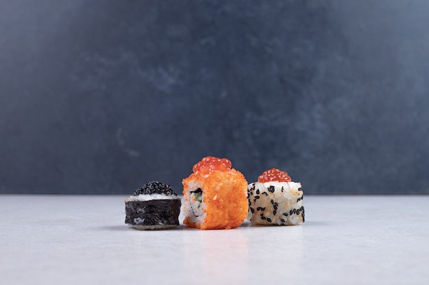 Maki, alaska and california sushi rolls on white table.