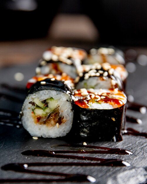 Maki roll with cucumber served with sauce and sesame seeds