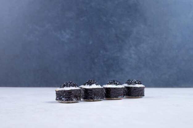 Maki rolls decorated with black caviar on white table. 