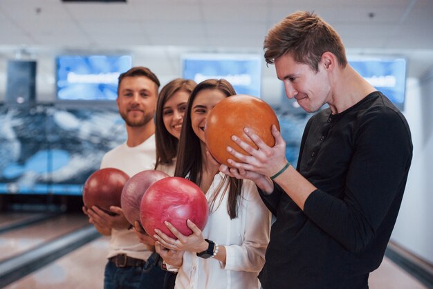 Making funny face. Young cheerful friends have fun in bowling club at their weekends