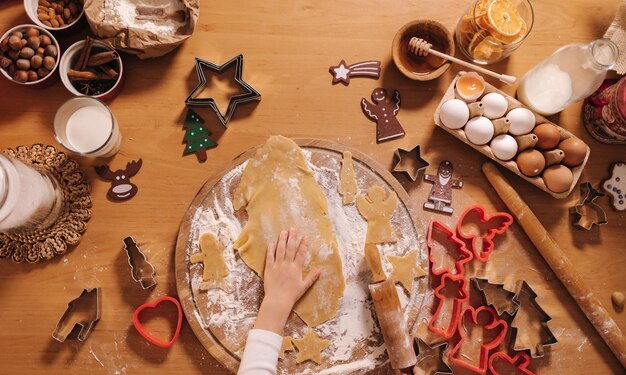 Делаем имбирные пряники дома маленькая девочка нарезает печенье из пряничного теста на рождество и новый год