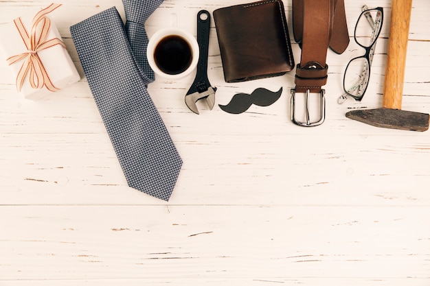 Male accessories near gift and cup of drink