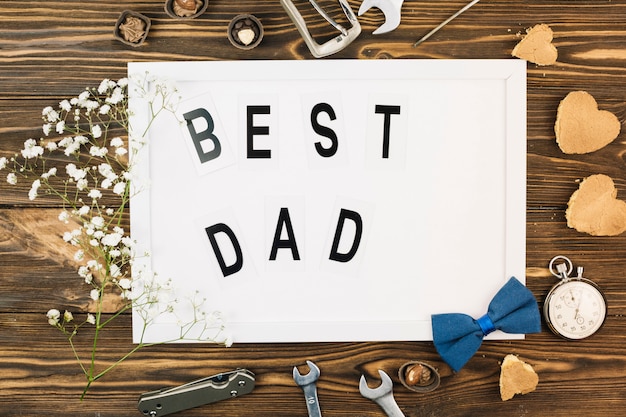 Male accessories near photo frame with best dad title and plant
