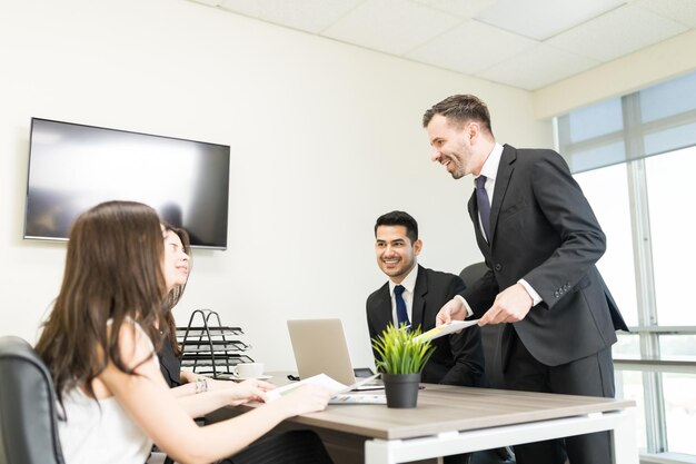 Male accountant showing financial document to female clients in office