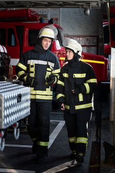 Пожарные мужчины и женщины работают вместе в костюмах и касках