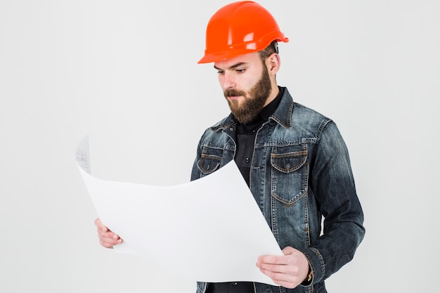 Free photo male architect looking at white blueprint against white backdrop