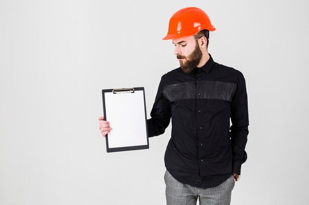 Male architect looking at white paper on clipboard