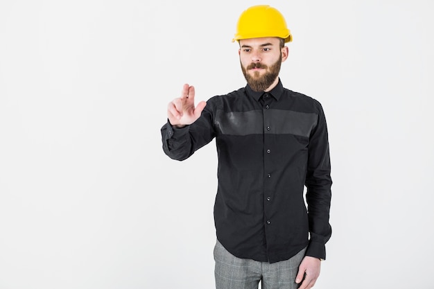 Мужской архитектор, одетый в желтый hardhat gesturing