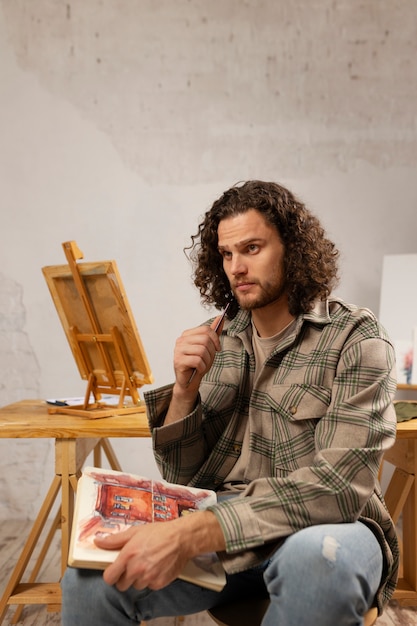 Художник-мужчина рисует в студии акварелью