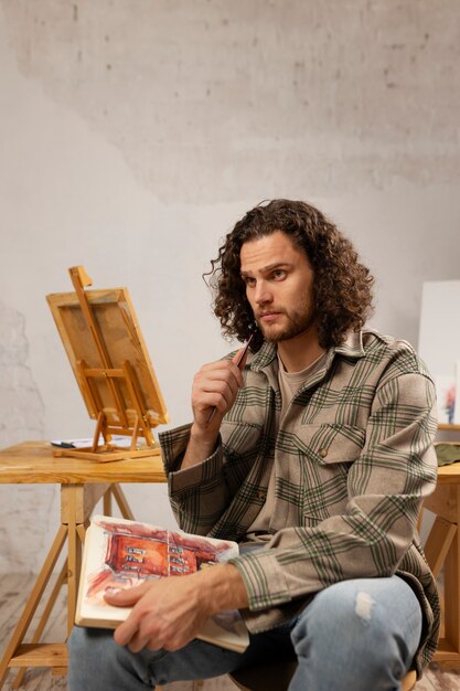 Male artist painting at studio with watercolors