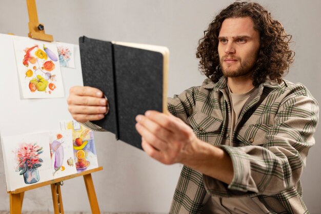 Male artist painting at studio with watercolors