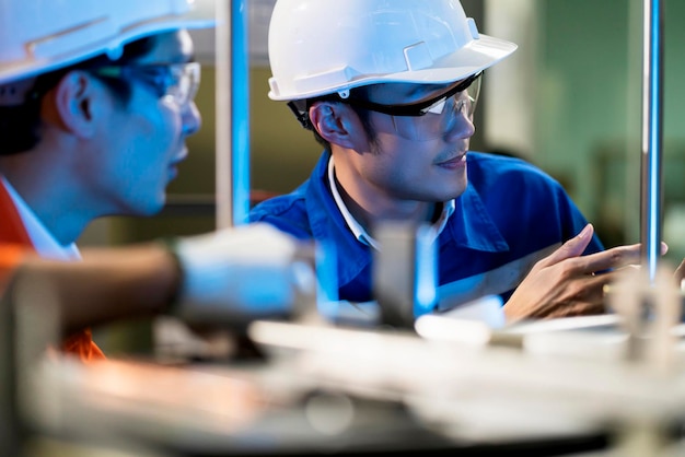 Free photo male asian engineer professional having a discussion standing by the machine in the factory two asian coworker brainstorm explaining and solves the process curcuit mother board of the machine