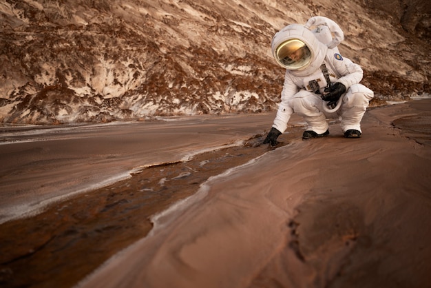 Мужчина-космонавт собирает камень во время космической миссии на другой планете