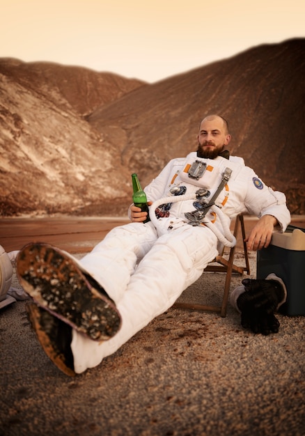 未知の惑星での宇宙ミッション中にビールを飲む男性宇宙飛行士 無料写真