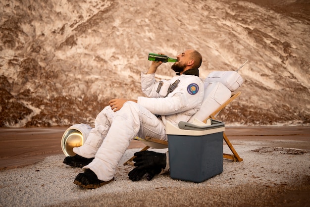 미지의 행성에서 우주 임무를 수행하는 동안 맥주를 마시는 남성 우주 비행사